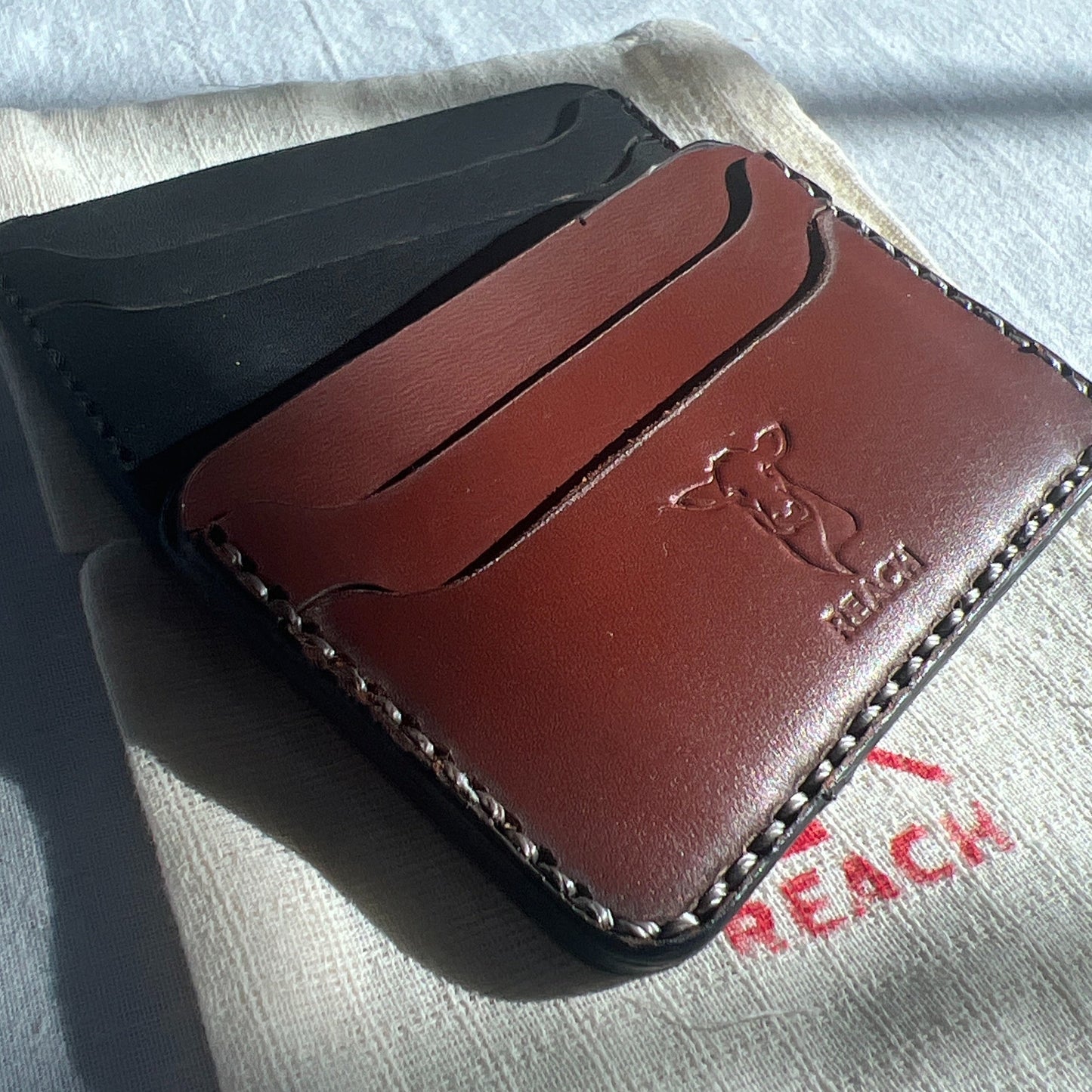 Brown leather wallet with visible brand logo on a textured surface