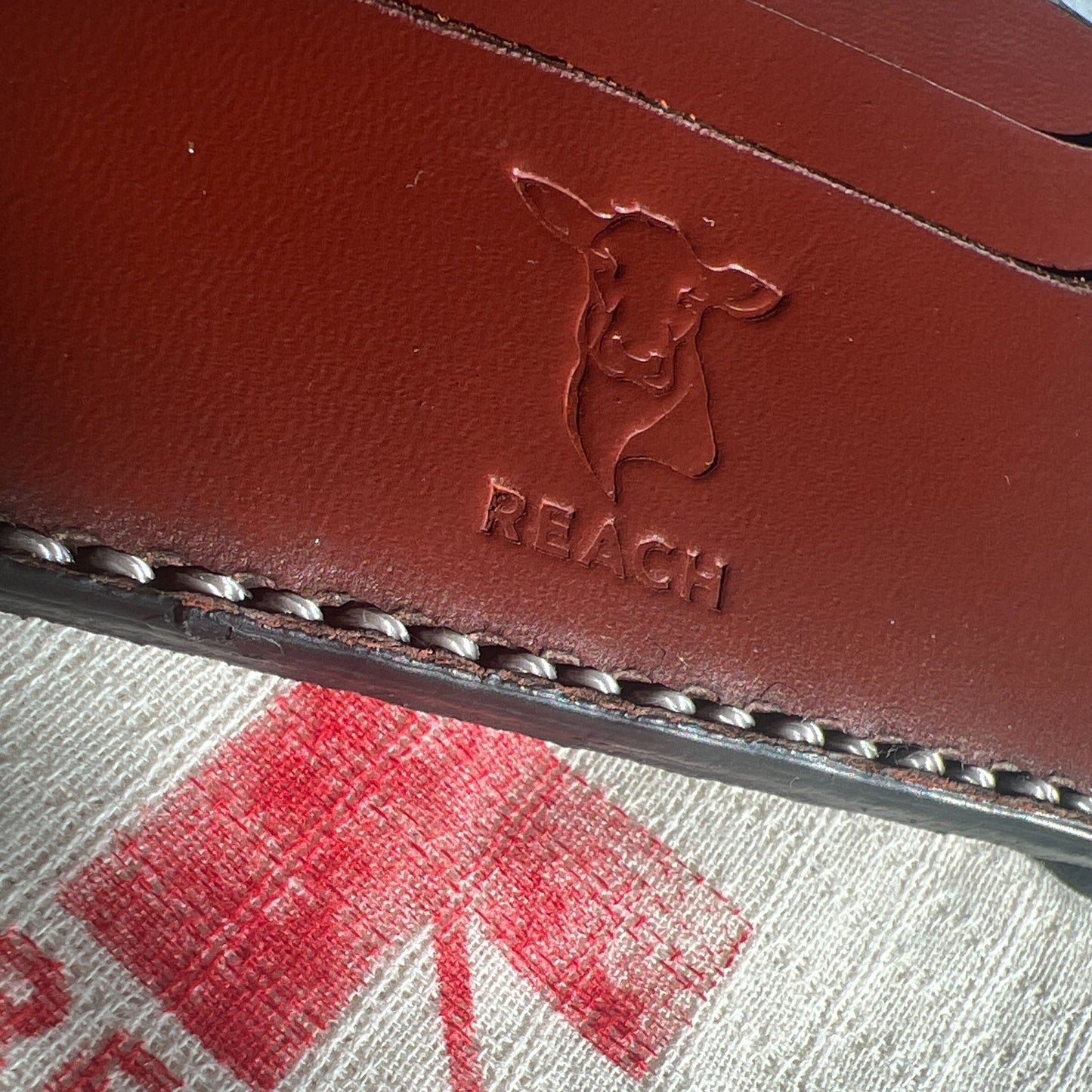Brown leather case with 'REACH' branding on a textured surface