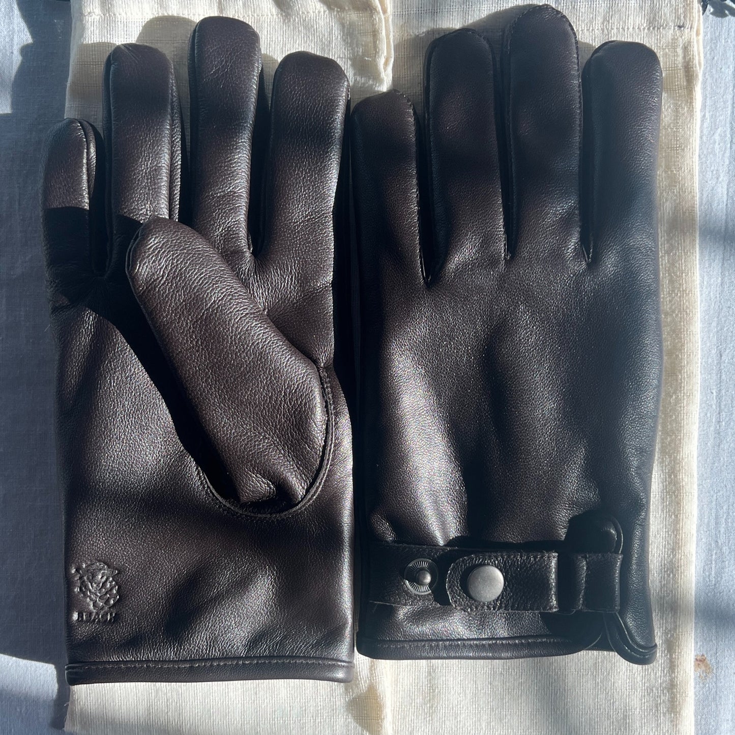 Pair of black leather gloves on a light fabric background