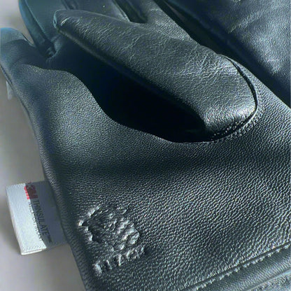 Black leather gloves with a brand logo on a textured surface