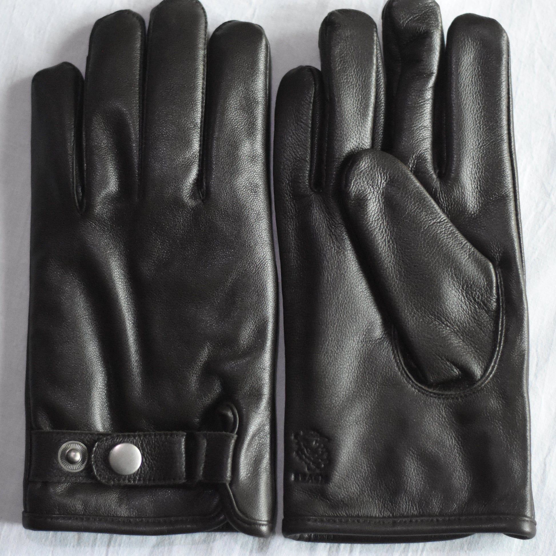Pair of black leather gloves on a light wooden surface